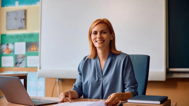 Pracownica placówki oświatowej przy biurku z dokumentami i laptopem