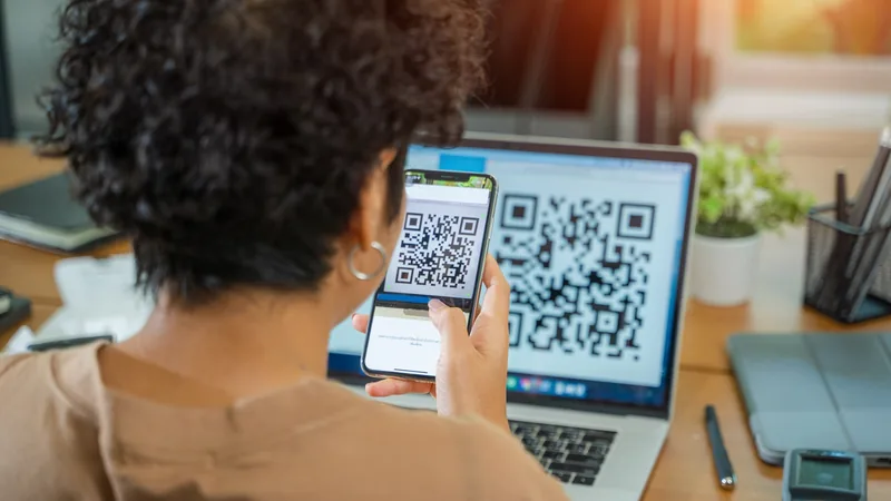 Pracownik skanuje telefonem kod QR wyświetlony na laptopie